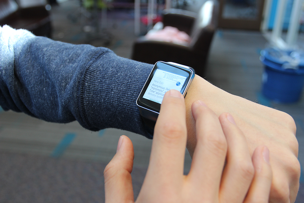 A user working on a document on a smartwatch using WearWrite, by leveraging a crowd to help trans­late their ideas into text.