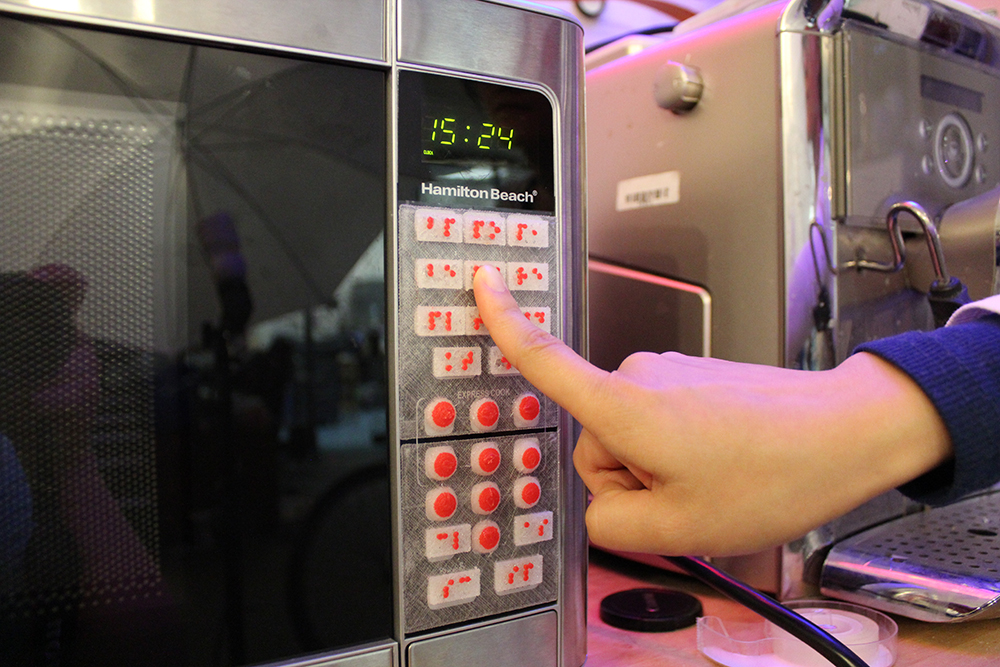 A user accessing the microwave augmented with tactile overlays generated by Facade.
